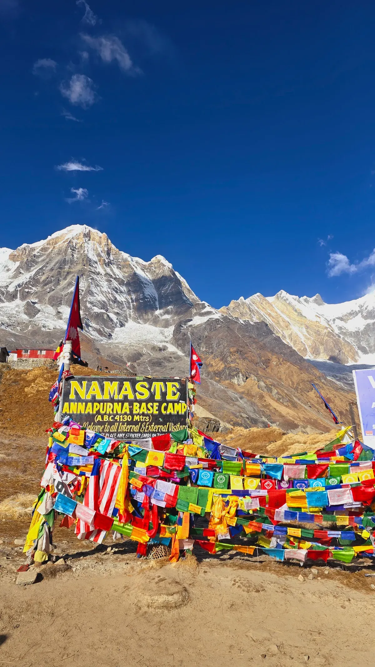 The Namaste Annapurna Base Camp sign and prayer flags at base camp.
