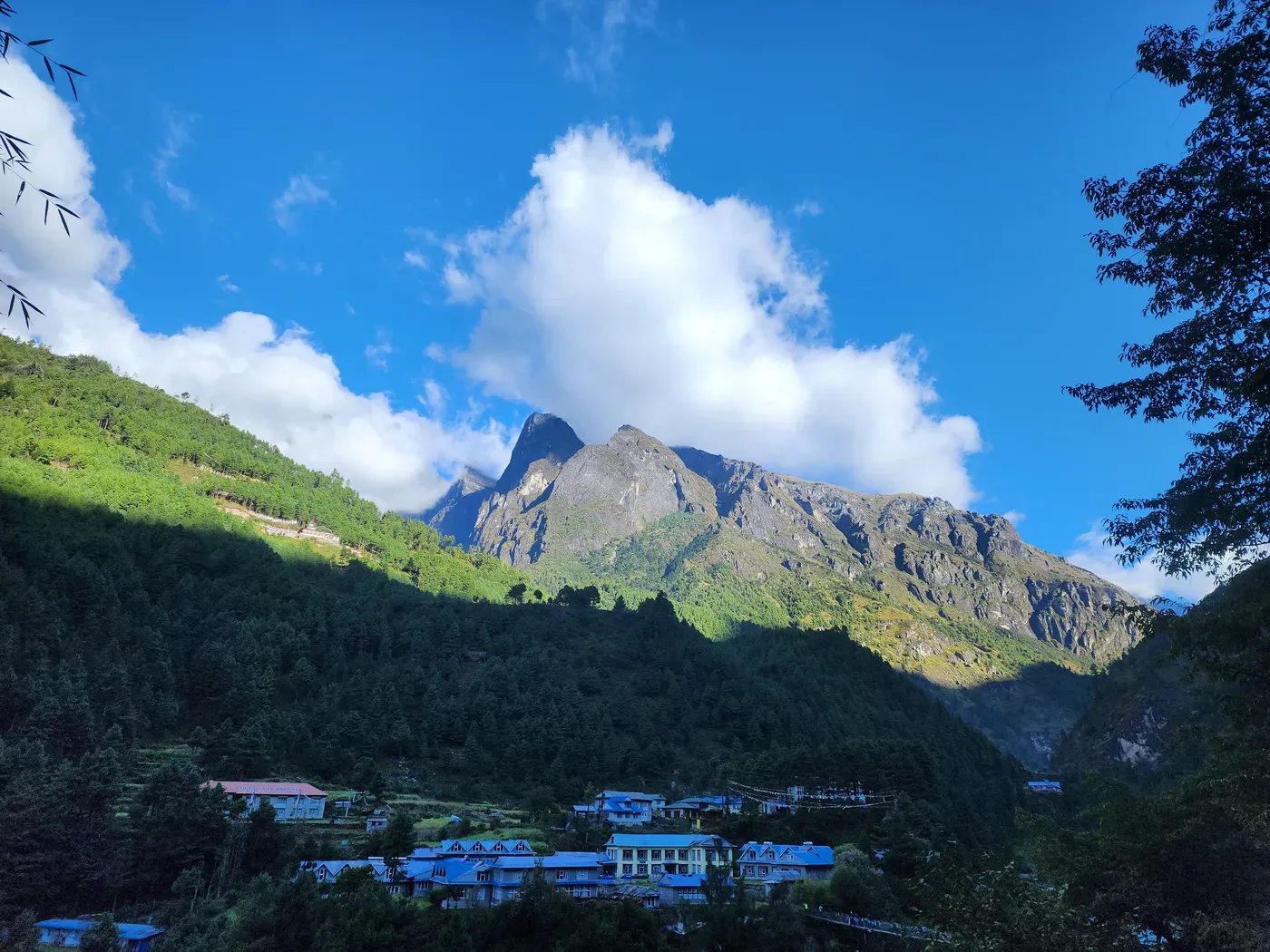 A Khumbu village under clear autumn skies, jagged snow peaks behind.