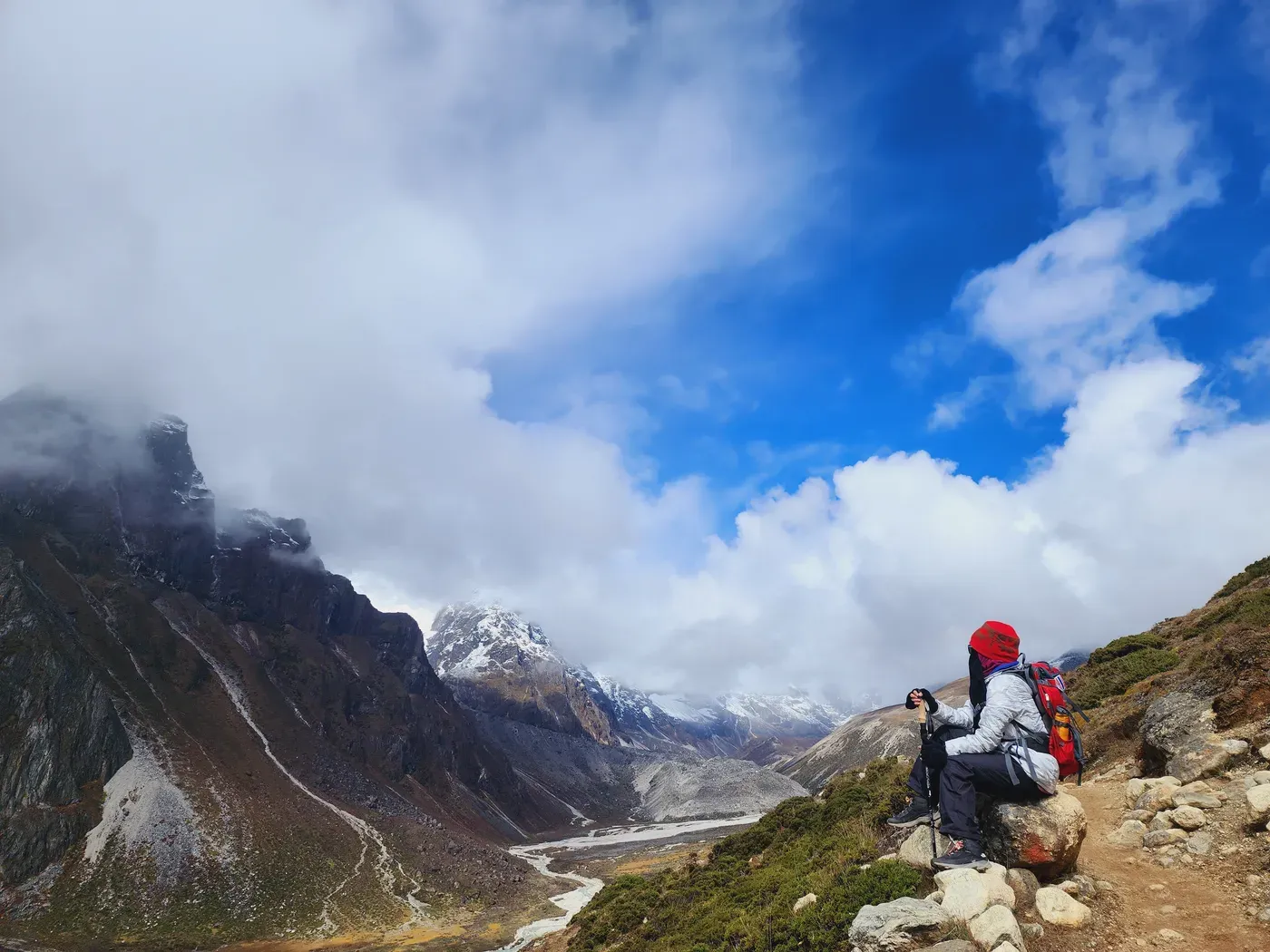 A trekker on the high, cloud-wrapped upper trail, bare rock and thin air all around.