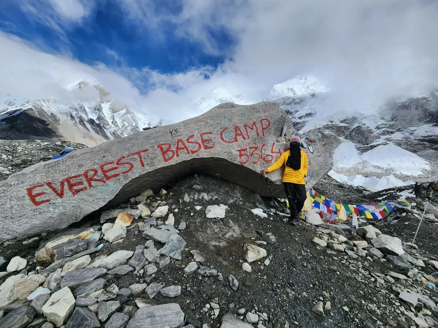 A rock painted with the words Everest Base Camp, hung with strings of prayer flags.