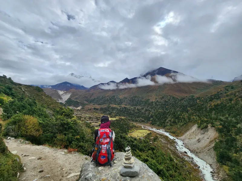 A trekker above a deep Khumbu valley, the trail dropping away below