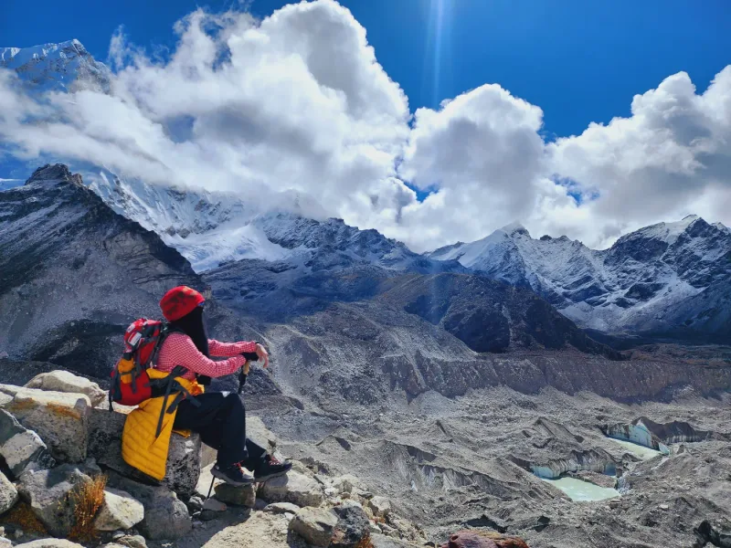 A trekker resting high on the trail, the Khumbu glacier and its ring of peaks below